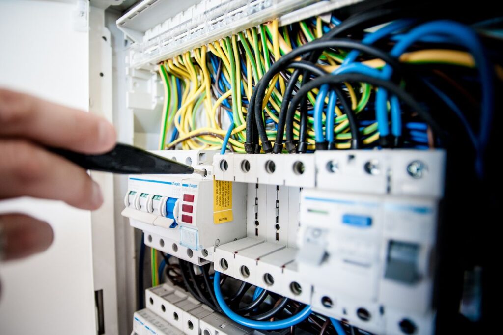 pexels photo 257736 257736 Hand of electrician working on a circuit breaker panel with colorful wires, ensuring safe electrical connections.